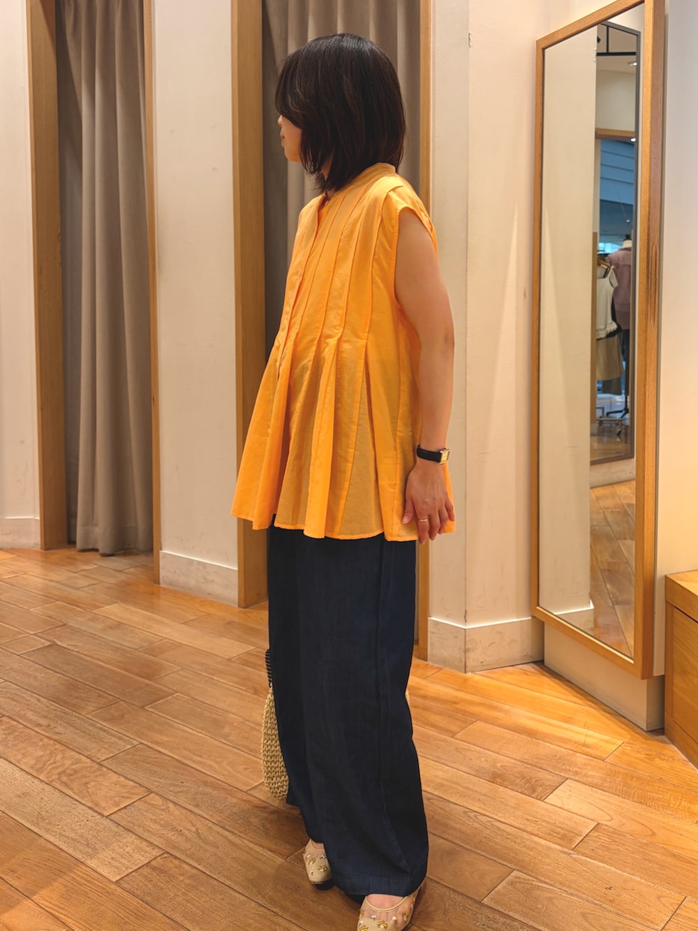 オレンジ系のシャツ/ブラウス、ブルー系のデニムパンツ、ベージュ系のトートバッグを着用したレディースの夏コーディネートの5枚目の写真