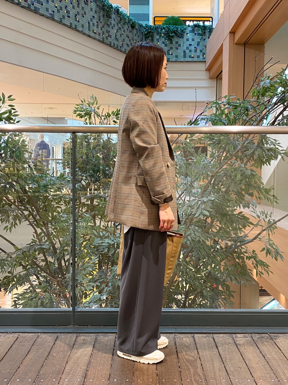 ベージュ系のテーラードジャケット、ホワイト系のベスト、イエロー系のショルダーバッグを着用したレディースの秋コーディネートの5枚目の写真