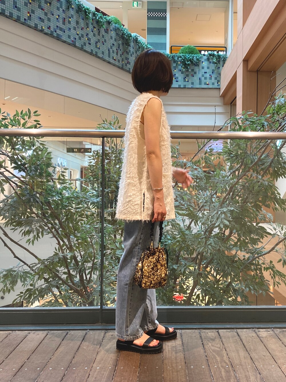 ホワイト系のベスト、ホワイト系のTシャツ/カットソー、ブルー系のデニムパンツを着用したレディースの夏コーディネートの4枚目の写真