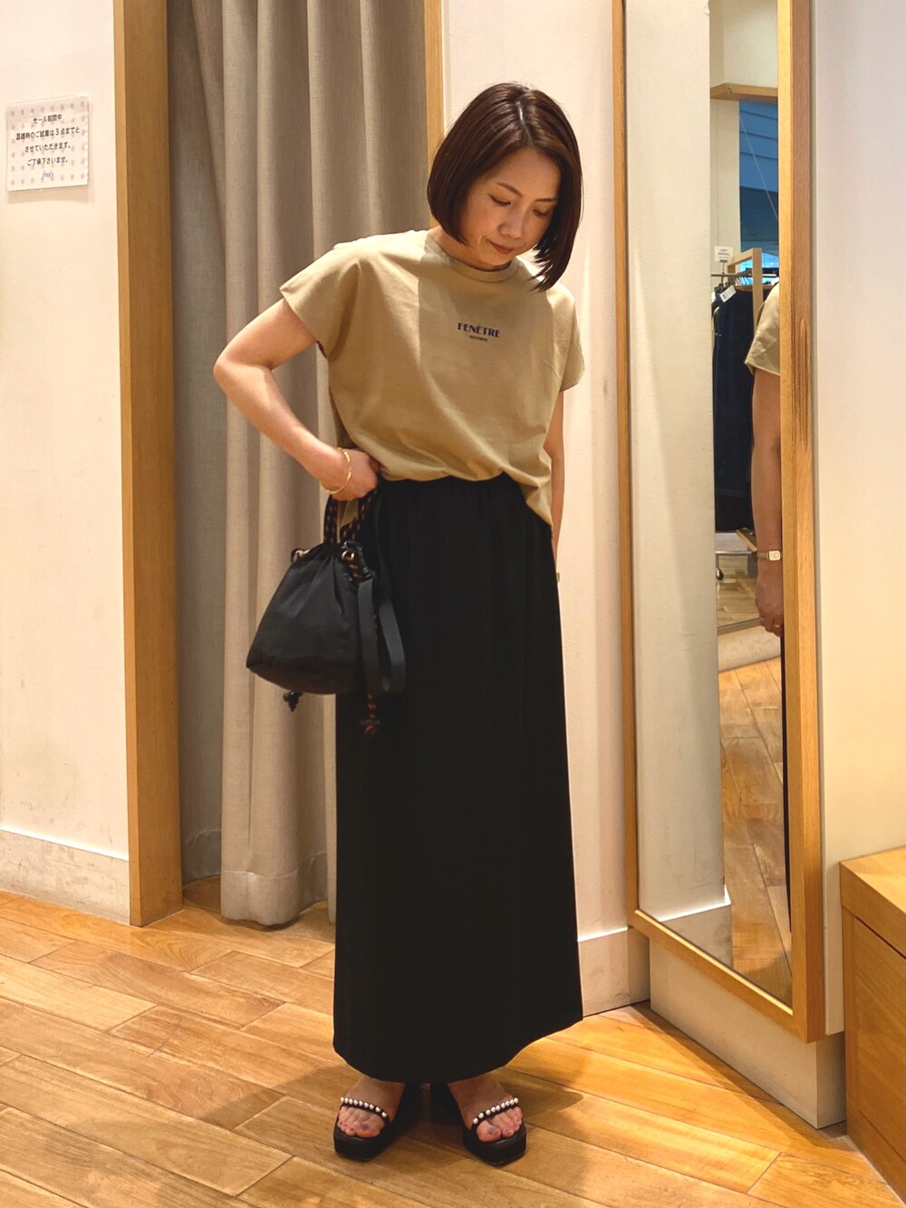 ブラック系のスカート、ブラック系のショルダーバッグ、イエロー系のTシャツ/カットソーを着用したレディースの夏コーディネートの2枚目の写真