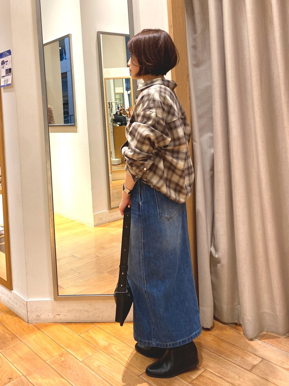 ブラウン系のシャツ/ブラウス、ブルー系のデニムスカート、ブラック系のショルダーバッグを着用したレディースの秋コーディネートの4枚目の写真