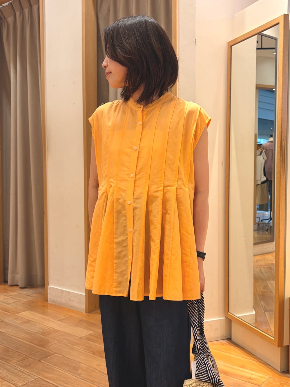 オレンジ系のシャツ/ブラウス、ブルー系のデニムパンツ、ベージュ系のトートバッグを着用したレディースの夏コーディネートの3枚目の写真
