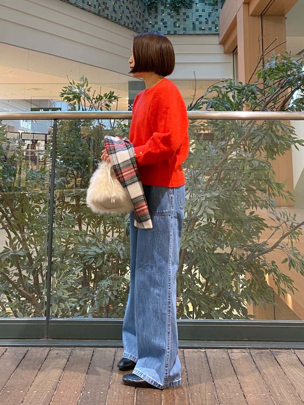 レッド系のニット/セーター、ブルー系のデニムパンツ、ベージュ系のハンドバッグを着用したレディースの冬コーディネートの4枚目の写真