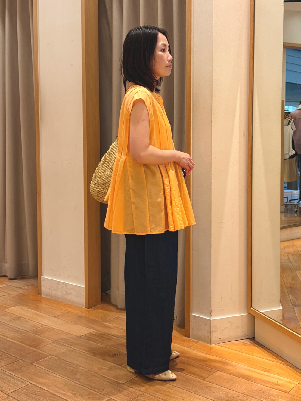 オレンジ系のシャツ/ブラウス、ブルー系のデニムパンツ、ベージュ系のトートバッグを着用したレディースの夏コーディネートの8枚目の写真