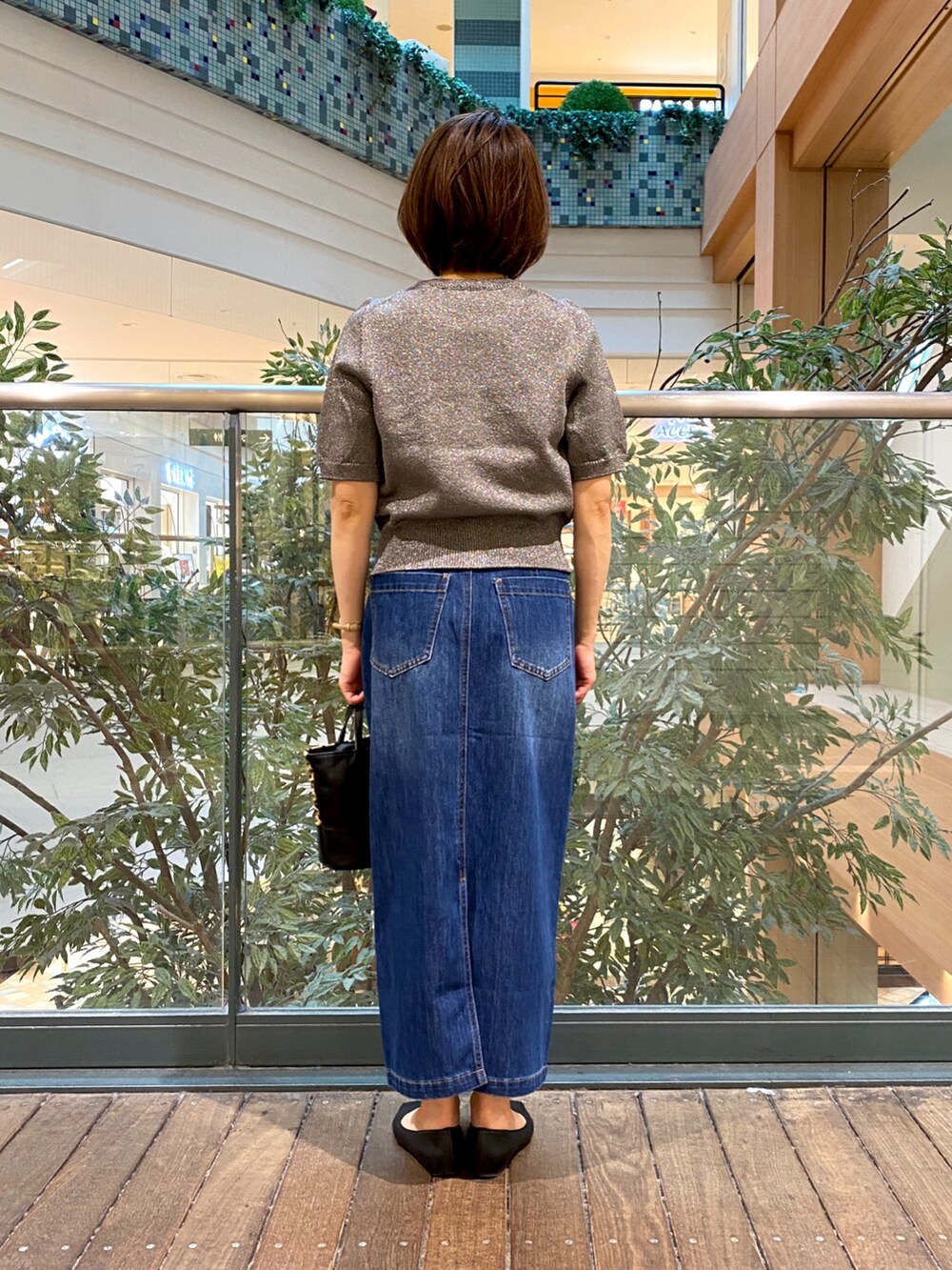 グレー系のニット/セーター、ブルー系のデニムスカート、ベージュ系のショルダーバッグを着用したレディースの秋コーディネートの5枚目の写真