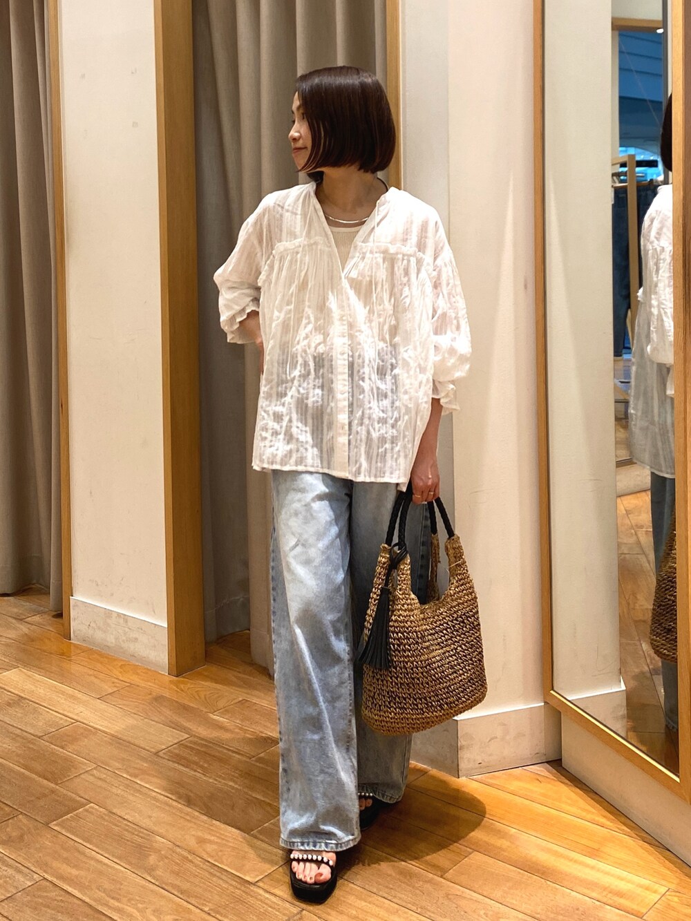 ホワイト系のシャツ/ブラウス、ブラウン系のかごバッグ、ブルー系のデニムパンツを着用したレディースの夏コーディネートの3枚目の写真