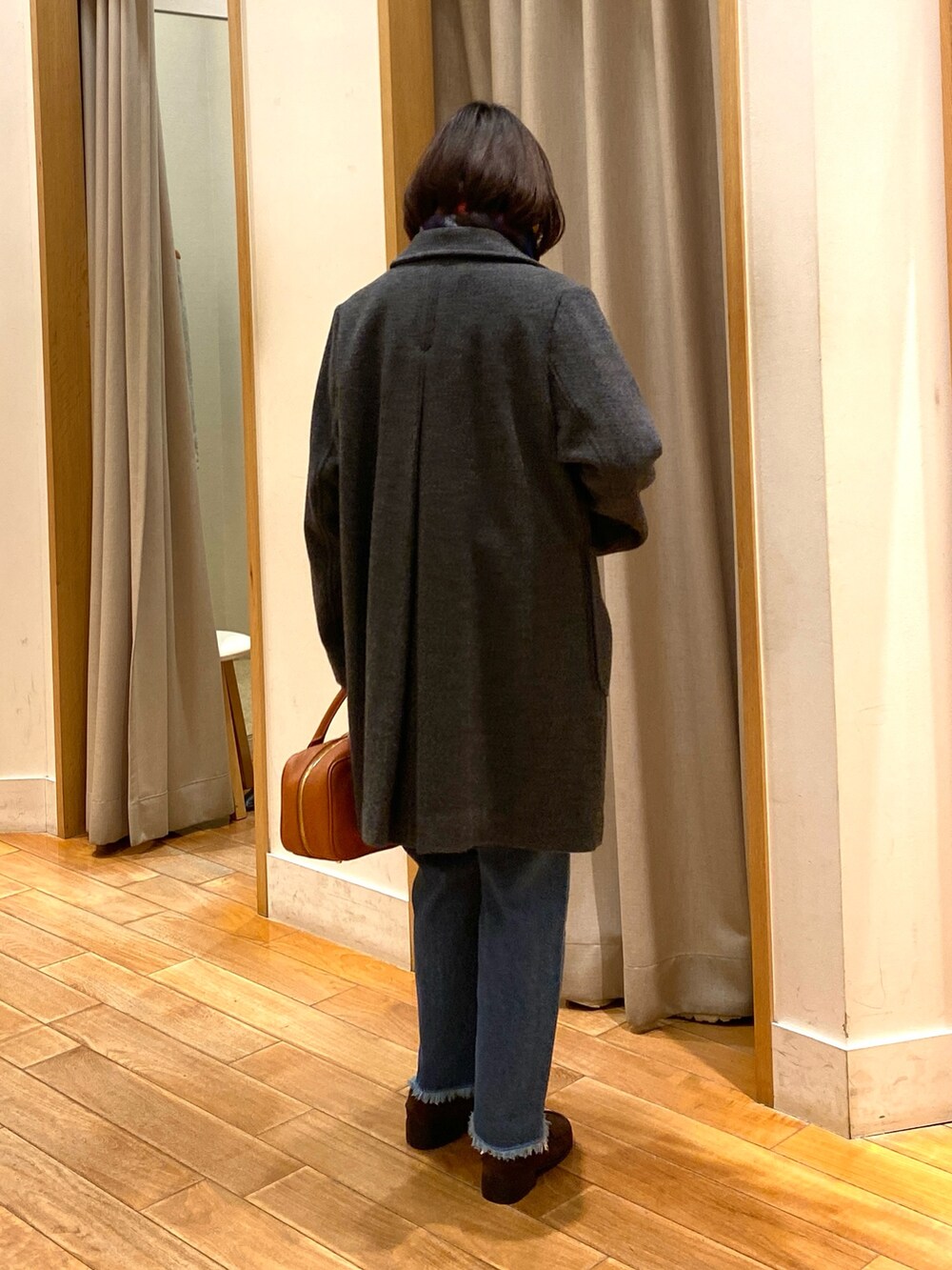 グレー系のダッフルコート、ブルー系のニット/セーター、ブルー系のデニムパンツを着用したレディースの冬コーディネートの6枚目の写真