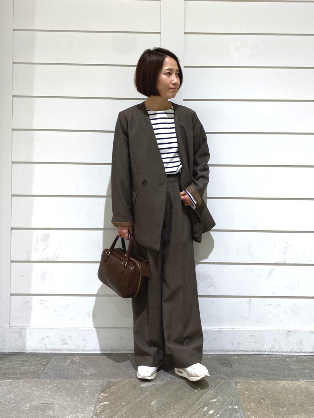 ブラウン系のハンドバッグ、ホワイト系のTシャツ/カットソー、ブラウン系のノーカラージャケットを着用したレディースの秋コーディネートの2枚目の写真