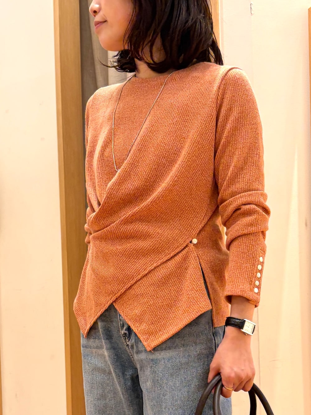 ブルー系のデニムパンツ、ブラウン系のボストンバッグ、オレンジ系のTシャツ/カットソーを着用したレディースの秋コーディネートの4枚目の写真