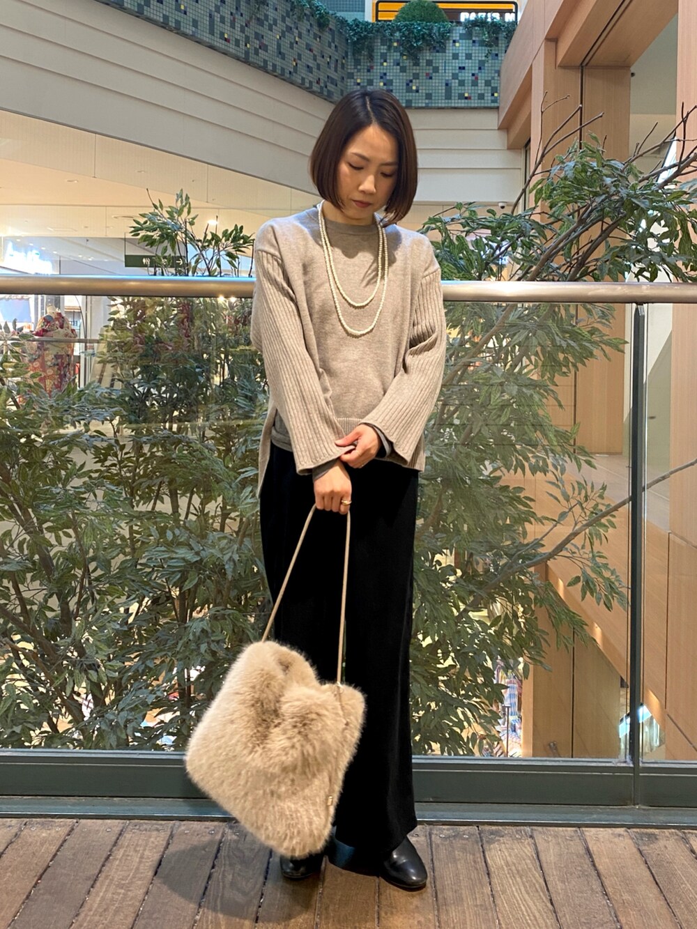 ブラック系のその他パンツ、ベージュ系のハンドバッグ、ベージュ系のニット/セーターを着用したレディースの冬コーディネートの2枚目の写真