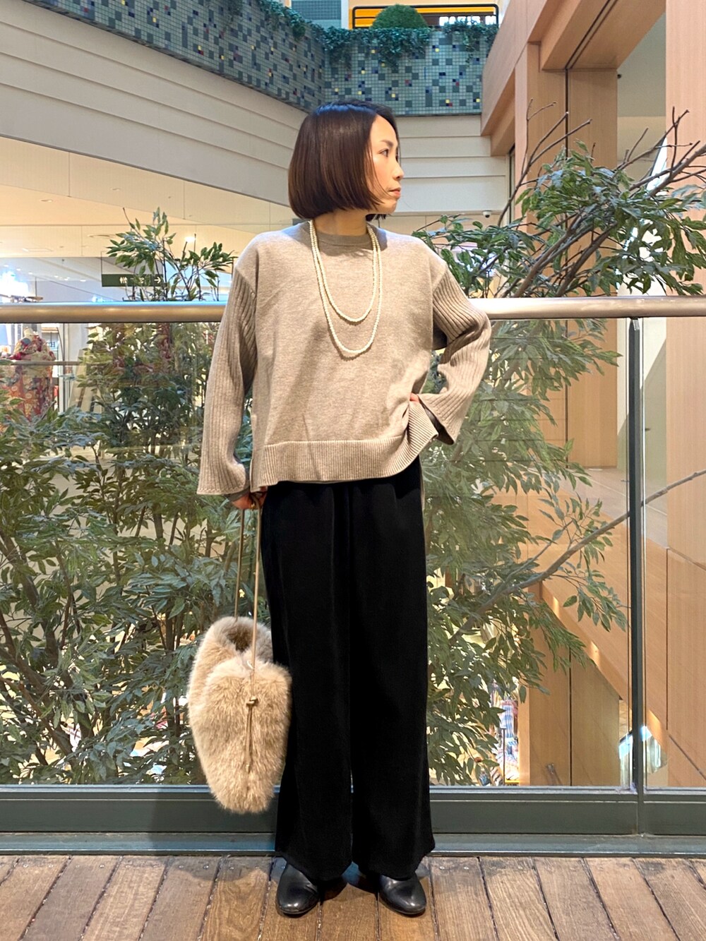 ブラック系のその他パンツ、ベージュ系のハンドバッグ、ベージュ系のニット/セーターを着用したレディースの冬コーディネートの3枚目の写真