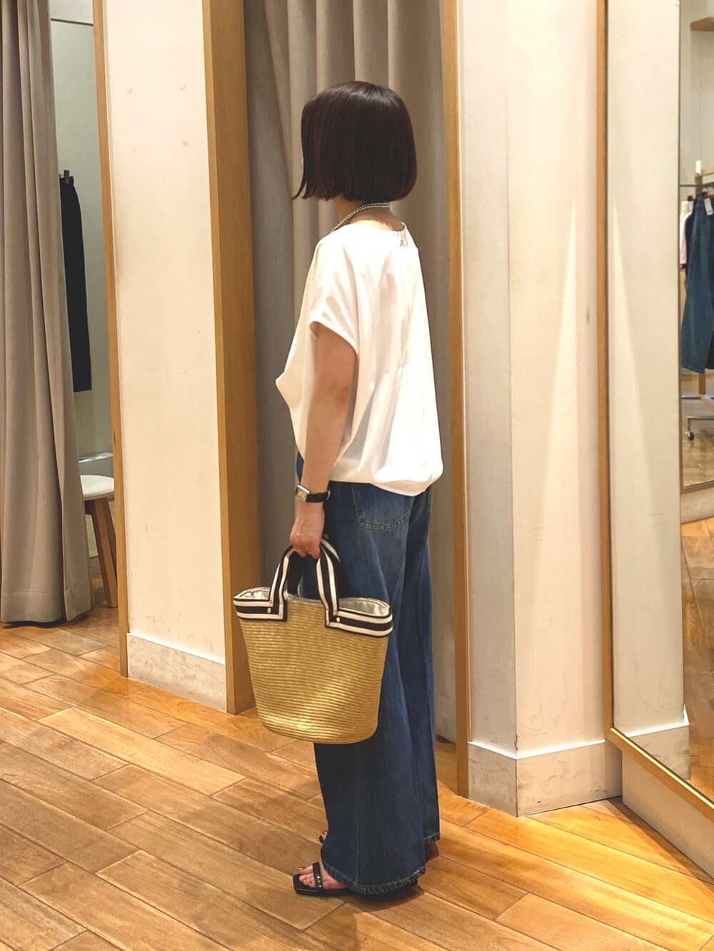 ブルー系のデニムパンツ、ホワイト系のTシャツ/カットソー、ベージュ系のかごバッグを着用したレディースの夏コーディネートの5枚目の写真
