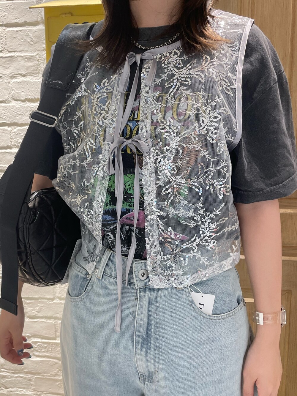 シルバー系のベスト、グレー系のTシャツ/カットソー、ブルー系のデニムパンツを着用したレディースの夏コーディネートの2枚目の写真