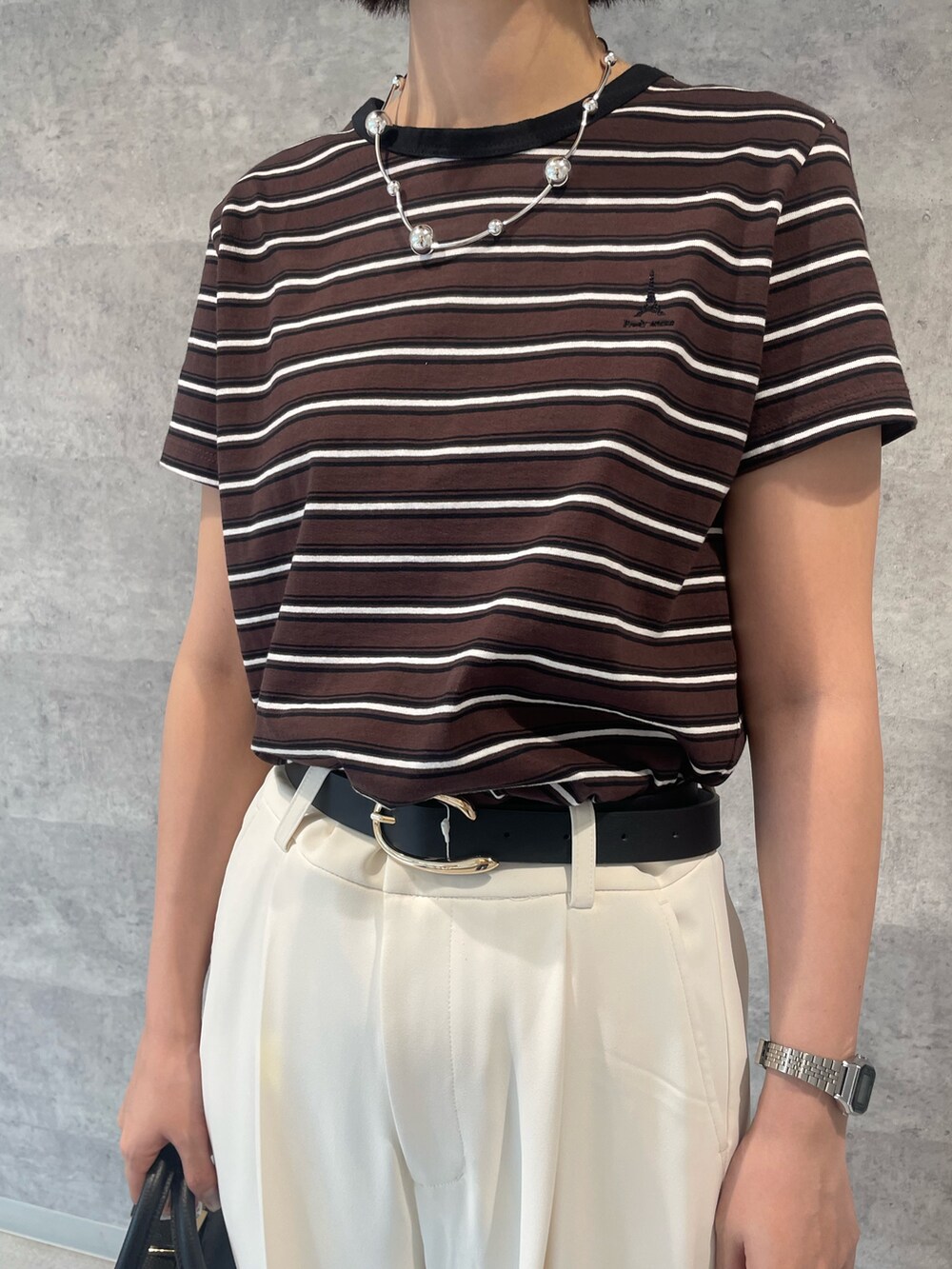 ベージュ系のTシャツ/カットソー、ホワイト系のスラックス、ブラック系のハンドバッグを着用したレディースの夏コーディネートの2枚目の写真