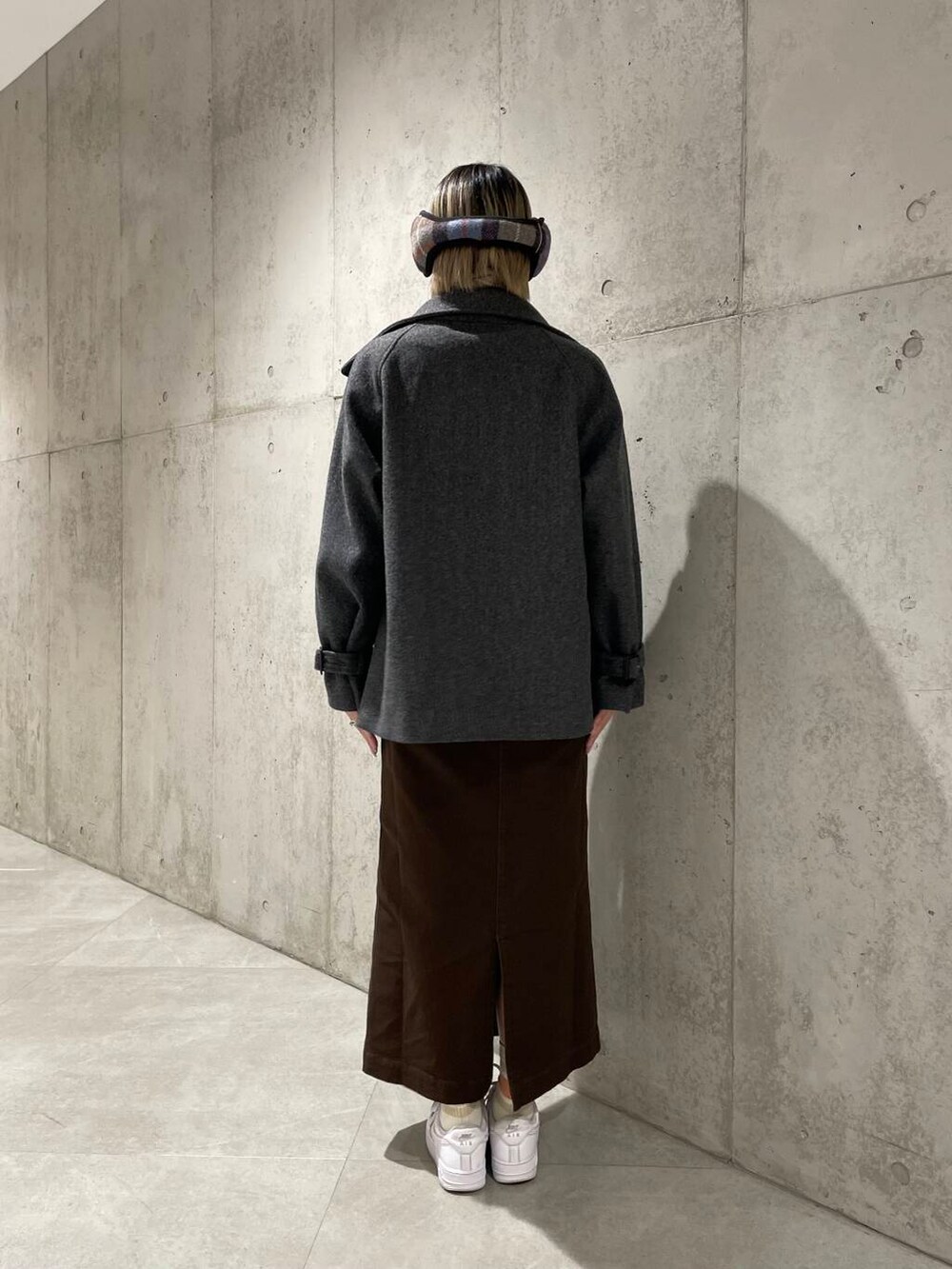 グレー系のトレンチコート、ブラック系のニット/セーター、ブラウン系のスカートを着用したレディースの冬コーディネートの4枚目の写真