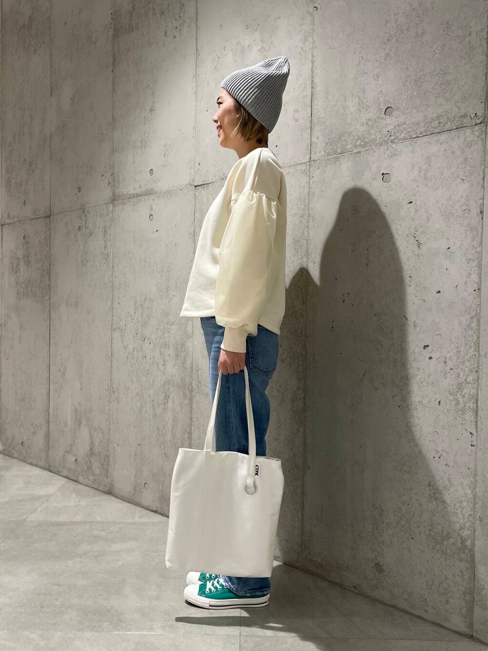 グリーン系のスニーカー、ホワイト系のトートバッグ、ホワイト系のスウェットを着用したレディースの冬コーディネートの2枚目の写真