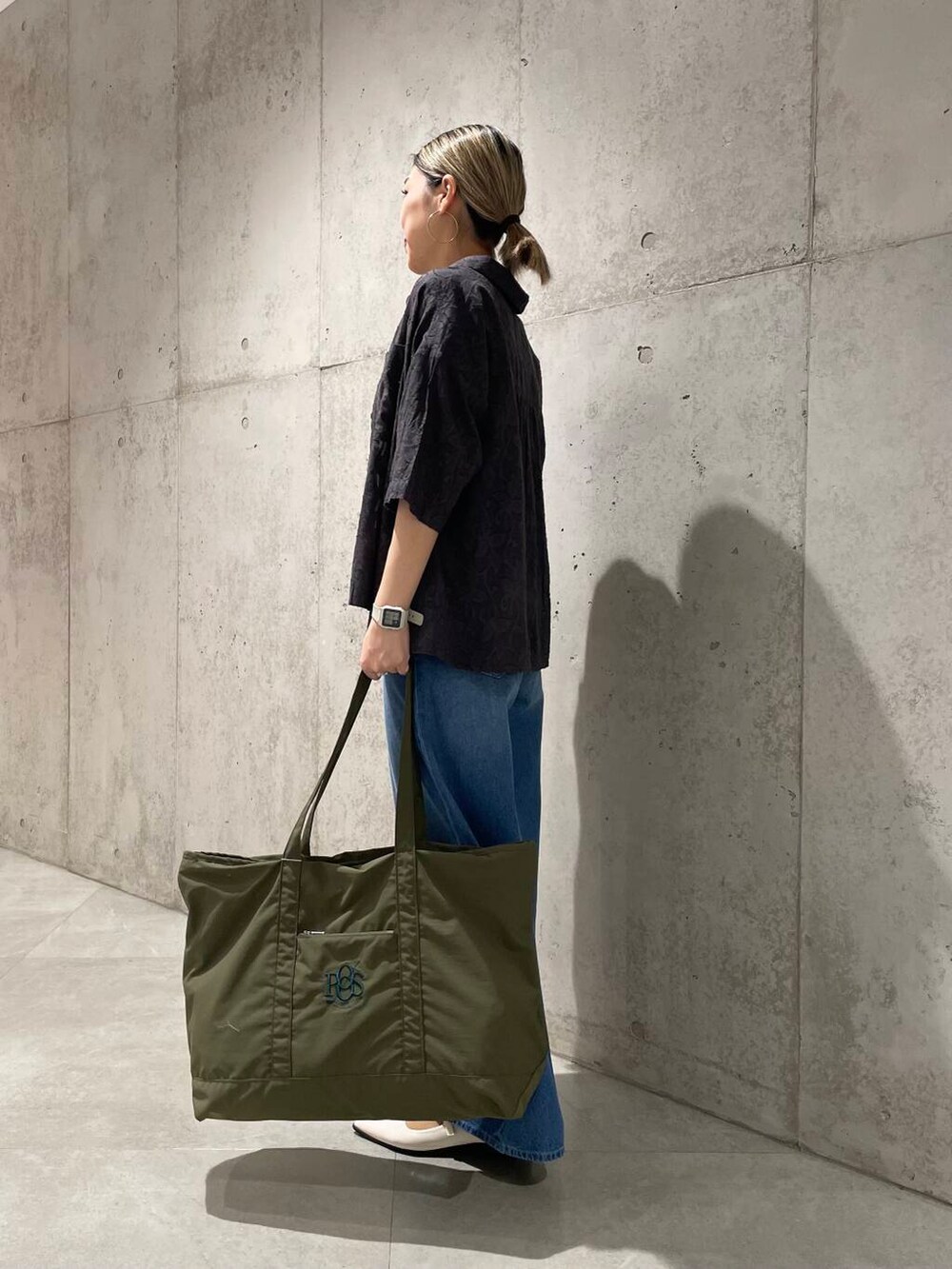 ブルー系のデニムパンツ、グリーン系のトートバッグ、グレー系のシャツ/ブラウスを着用したレディースの春コーディネートの2枚目の写真