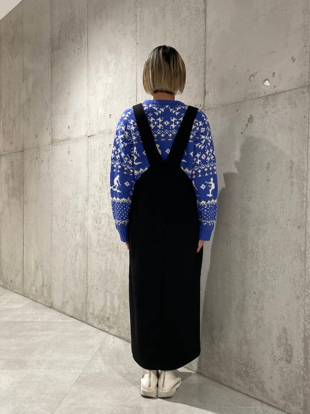 ブラック系のジャンパースカート、ブルー系のニット/セーターを着用したレディースの冬コーディネートの3枚目の写真