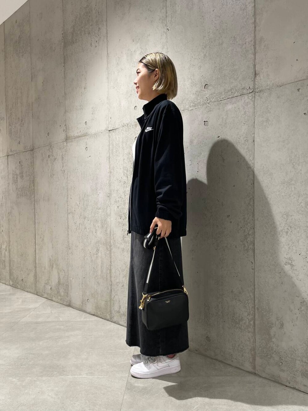 ブラック系のその他アウター、ブラック系のショルダーバッグ、ホワイト系のTシャツ/カットソーを着用したレディースの秋コーディネートの2枚目の写真