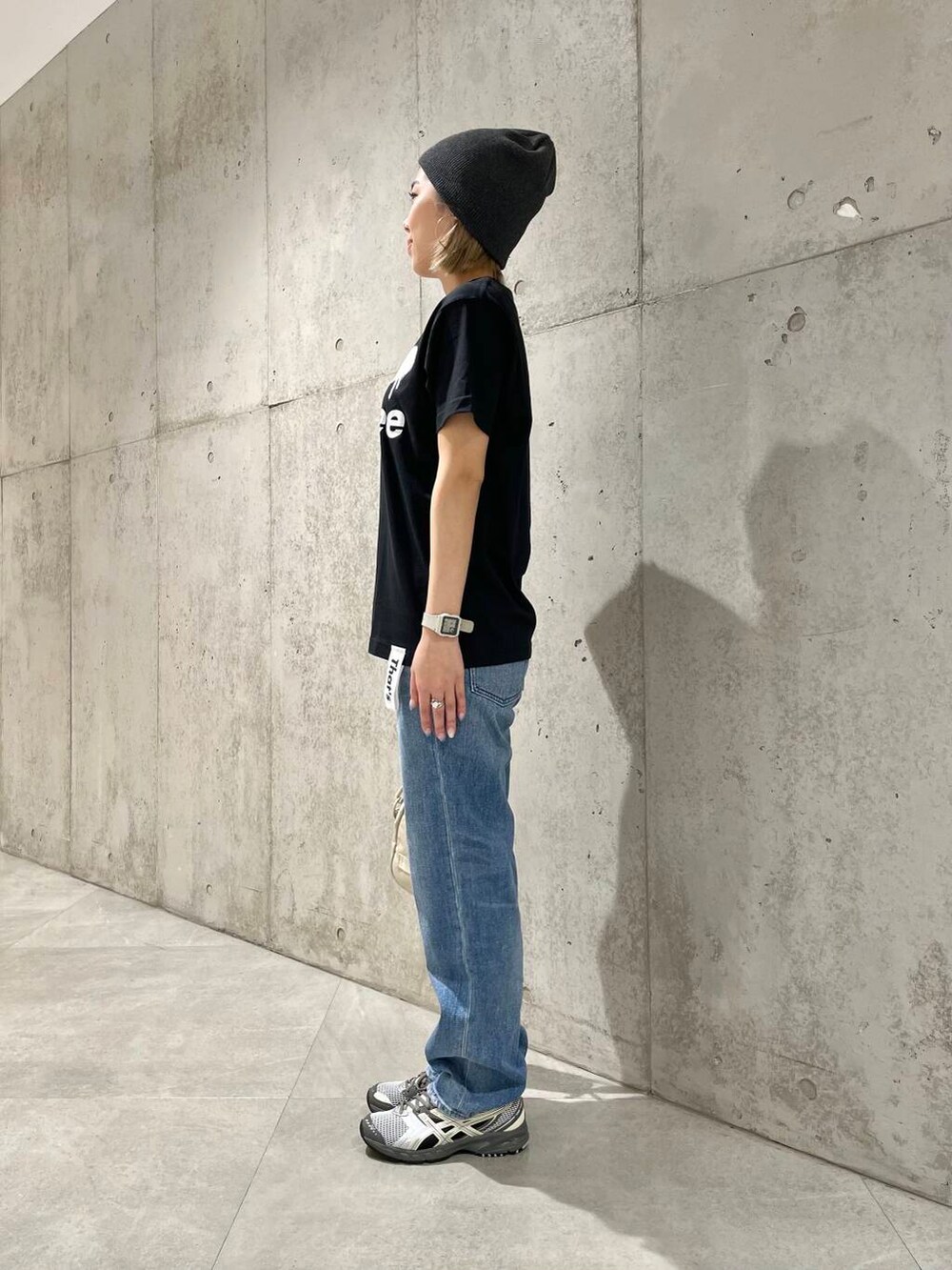 ブルー系のデニムパンツ、ブラック系のタンクトップ、ベージュ系のショルダーバッグを着用したレディースの春コーディネートの2枚目の写真