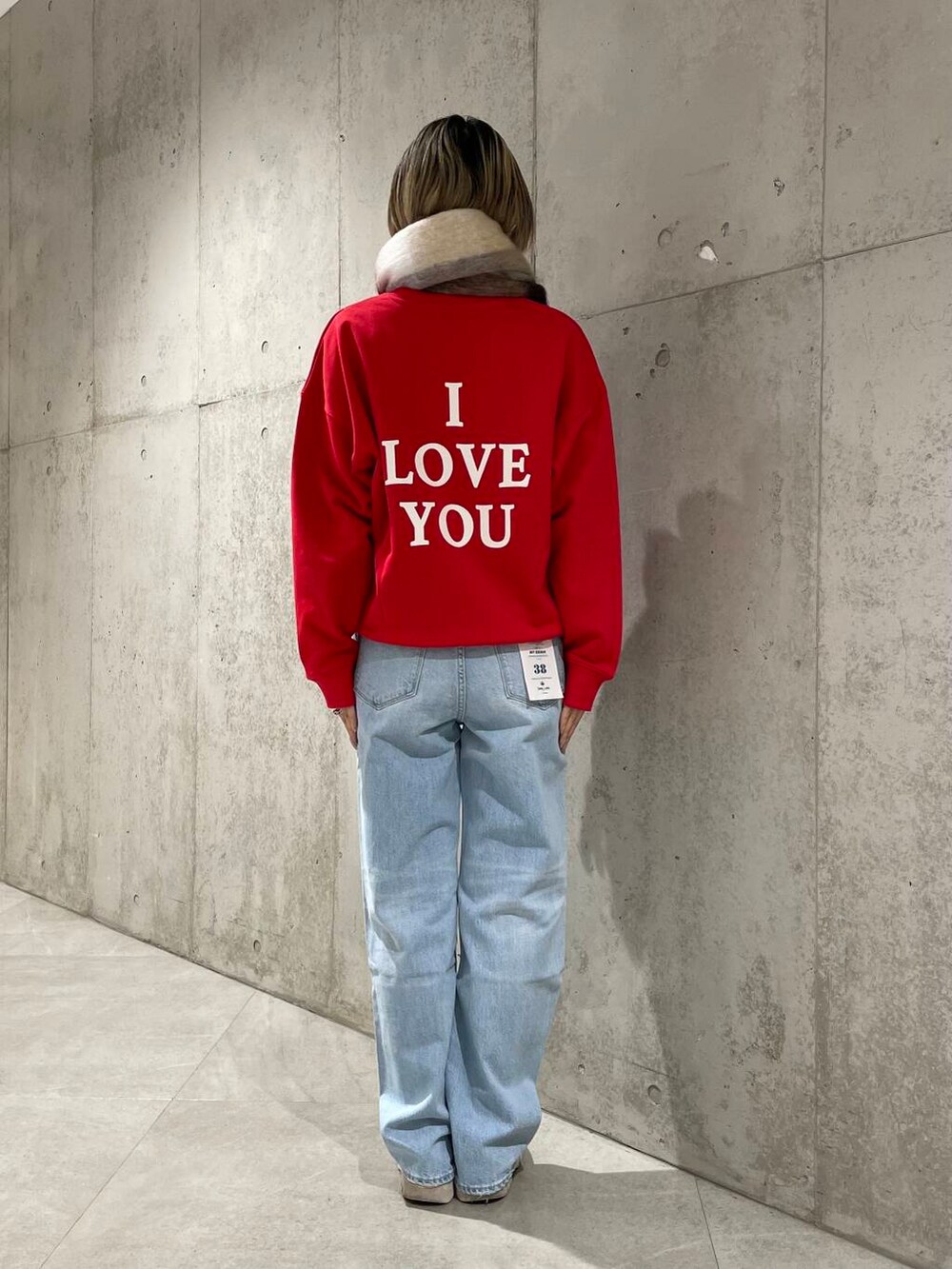 ブルー系のデニムパンツ、レッド系のスウェット、グレー系のマフラーを着用したレディースの冬コーディネートの3枚目の写真