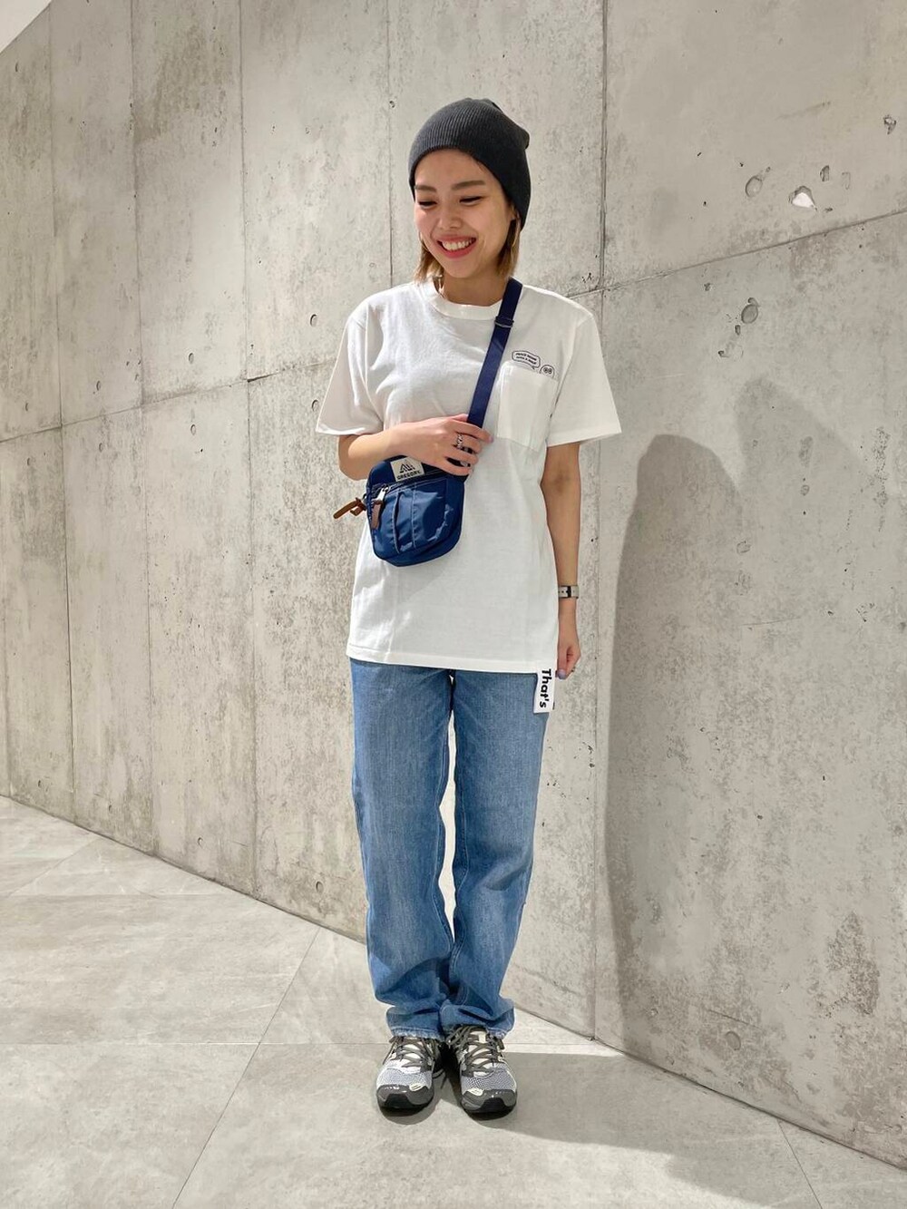 ブルー系のデニムパンツ、ブラック系のタンクトップ、ベージュ系のショルダーバッグを着用したレディースの春コーディネートの4枚目の写真