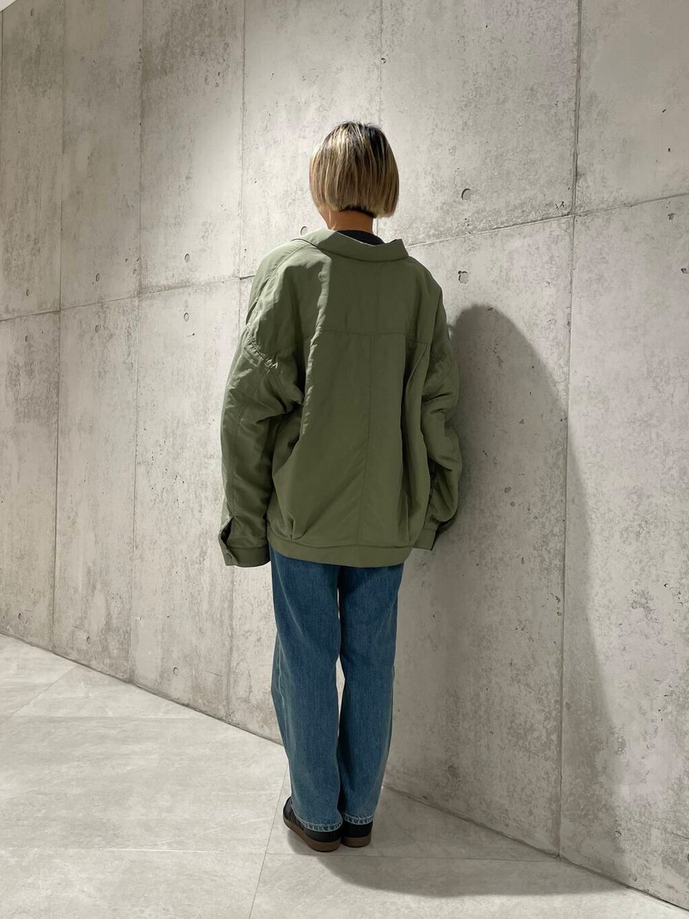 ブルー系のデニムパンツ、グリーン系のブルゾン、ブラック系のTシャツ/カットソーを着用したレディースの秋コーディネートの3枚目の写真