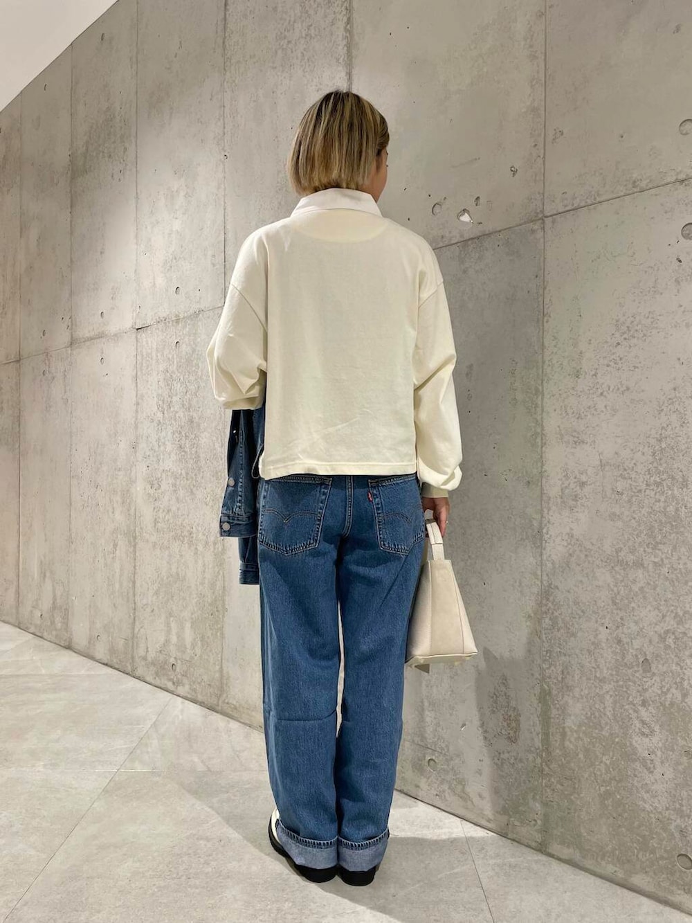 ベージュ系のショルダーバッグ、ホワイト系のローファー、ベージュ系のポロシャツを着用したレディースの夏コーディネートの3枚目の写真