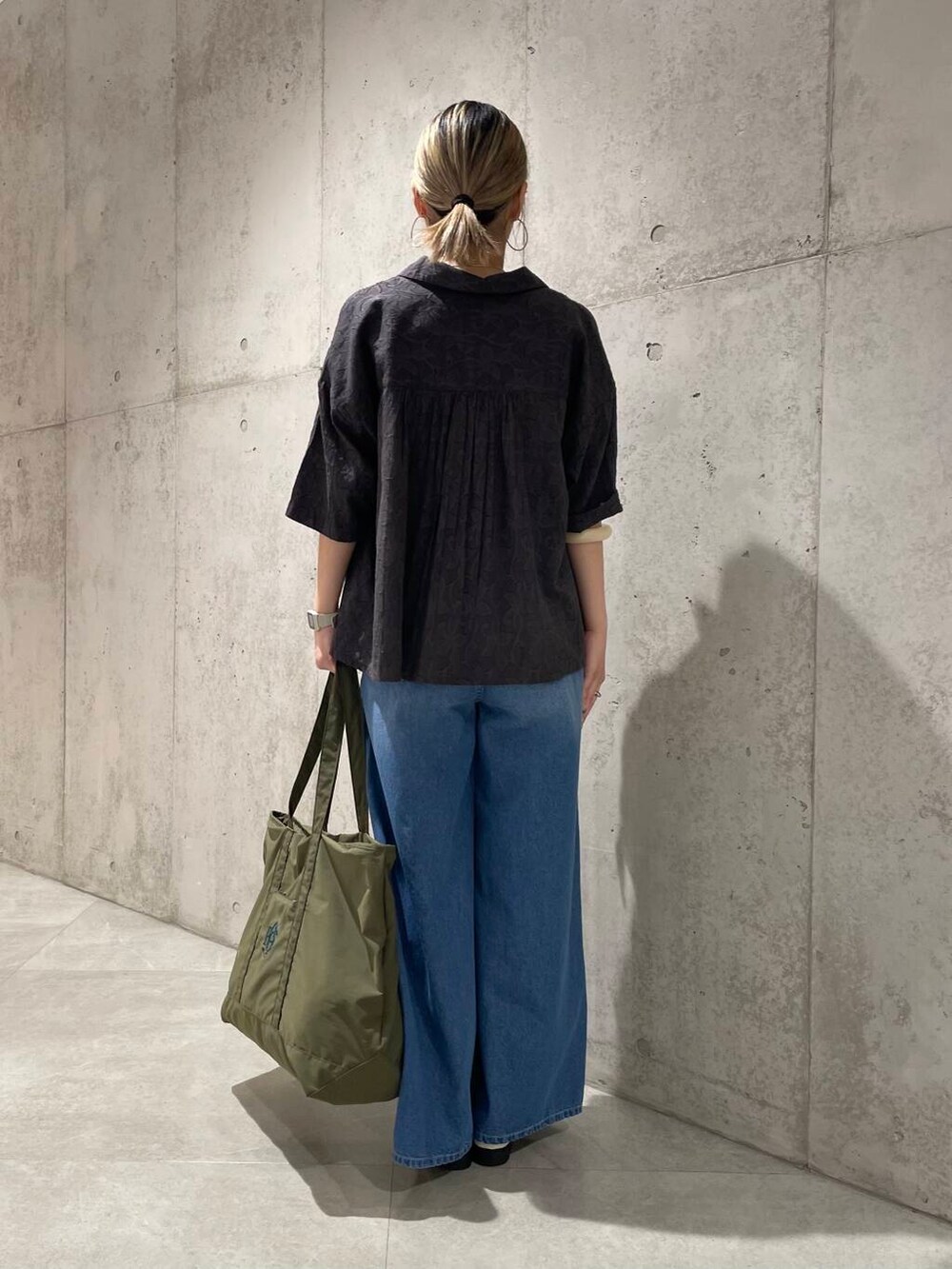 ブルー系のデニムパンツ、グリーン系のトートバッグ、グレー系のシャツ/ブラウスを着用したレディースの春コーディネートの3枚目の写真