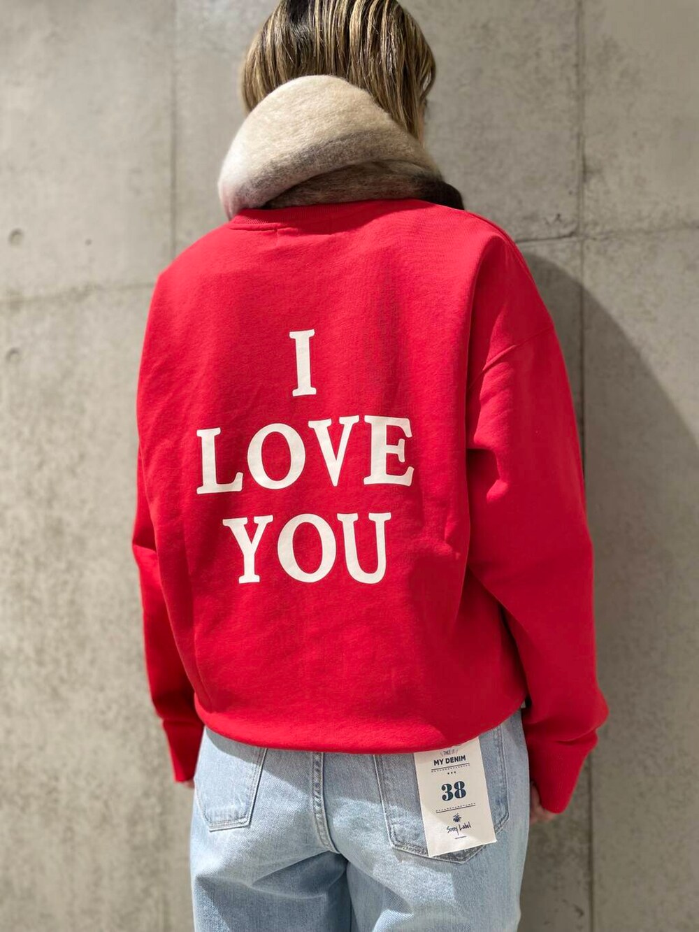 ブルー系のデニムパンツ、レッド系のスウェット、グレー系のマフラーを着用したレディースの冬コーディネートの4枚目の写真