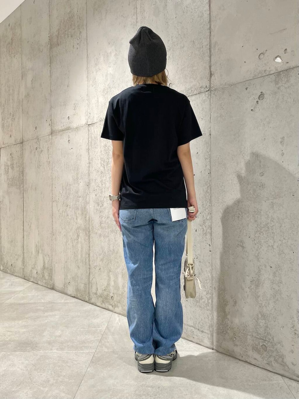 ブルー系のデニムパンツ、ブラック系のタンクトップ、ベージュ系のショルダーバッグを着用したレディースの春コーディネートの3枚目の写真