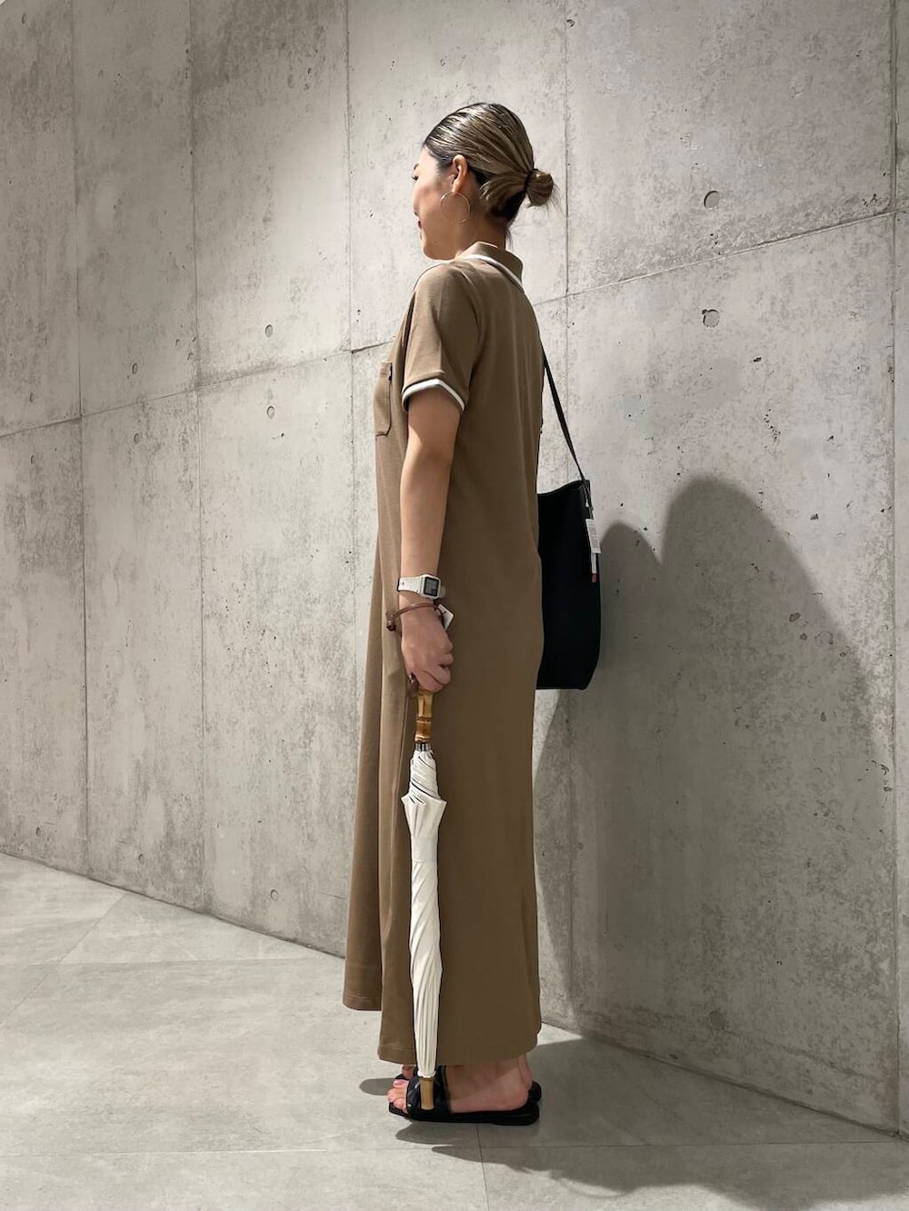 ブラック系のショルダーバッグ、ベージュ系のワンピース、ホワイト系の長傘を着用したレディースの夏コーディネートの3枚目の写真