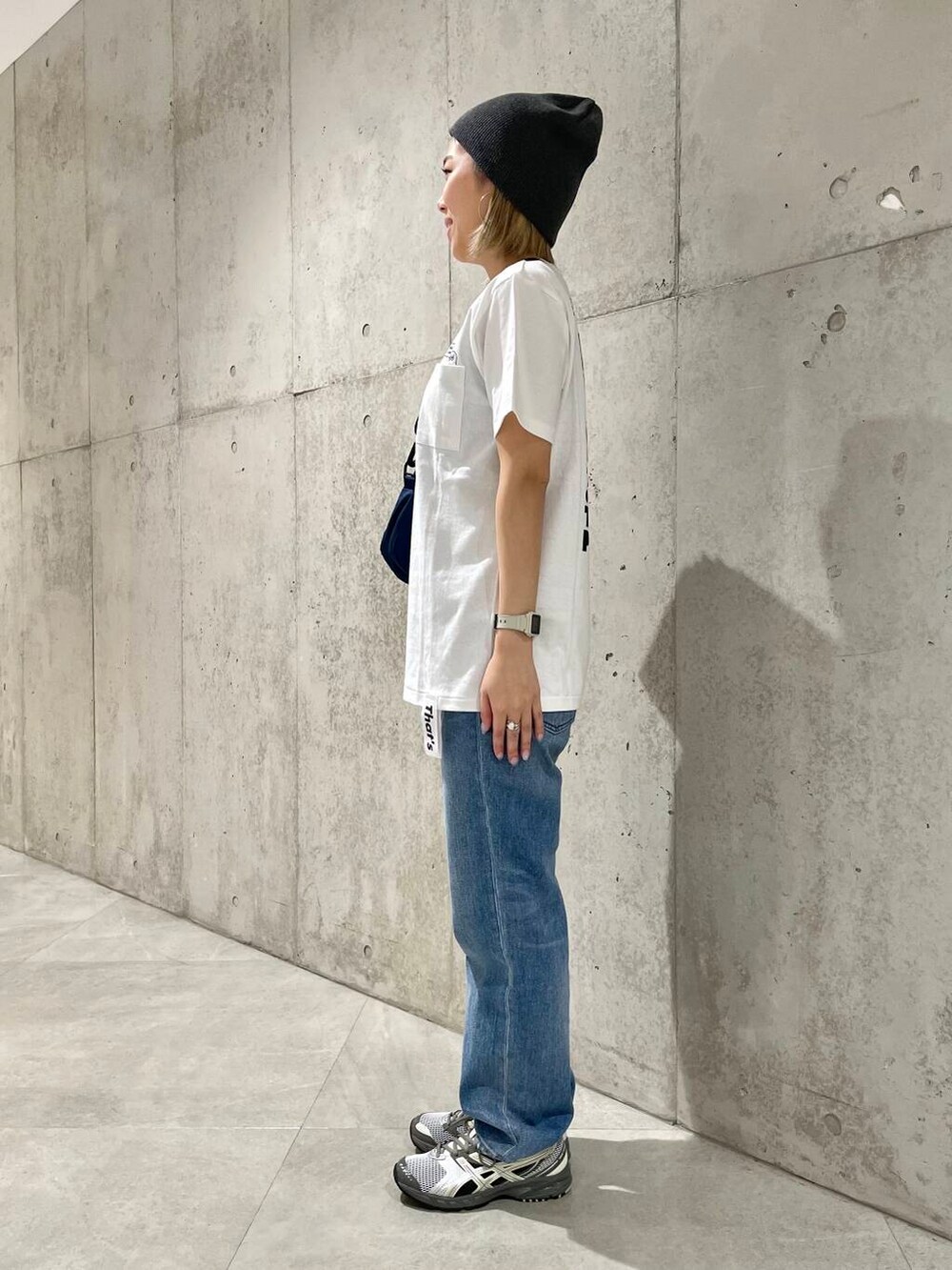 ブルー系のデニムパンツ、ブラック系のタンクトップ、ベージュ系のショルダーバッグを着用したレディースの春コーディネートの5枚目の写真