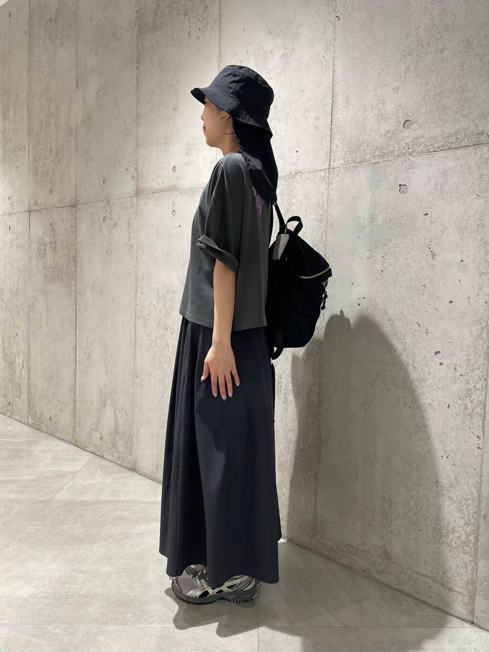 ブラック系のTシャツ/カットソー、ブラック系のバックパック/リュック、グレー系のスカートを着用したレディースの夏コーディネートの2枚目の写真