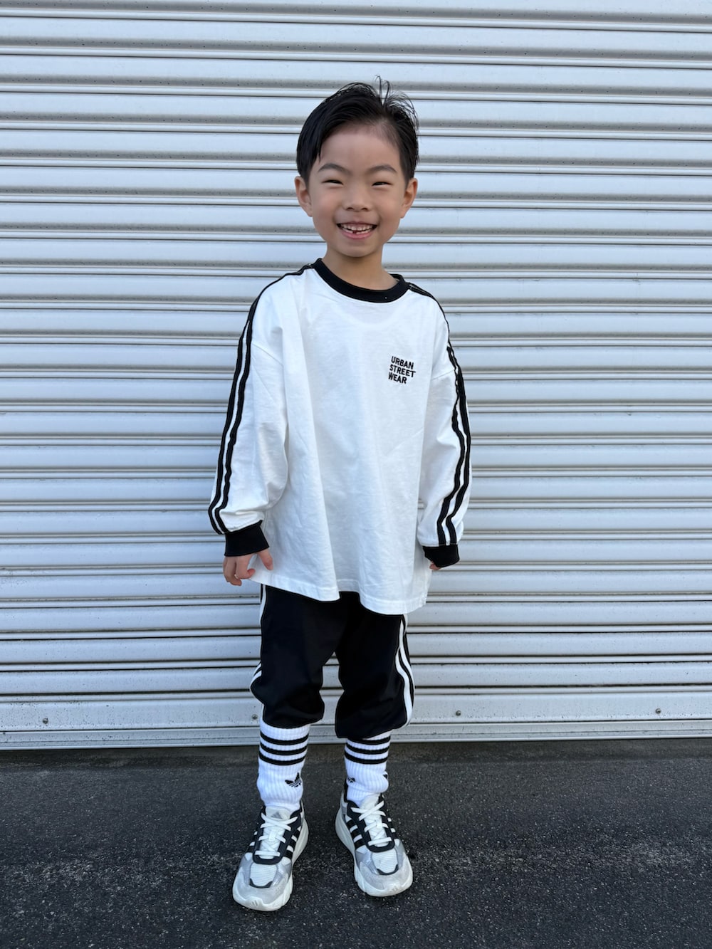 ホワイト系のTシャツ/カットソー、ブラック系のその他パンツ、ホワイト系のスニーカーを着用したキッズの春コーディネートの2枚目の写真