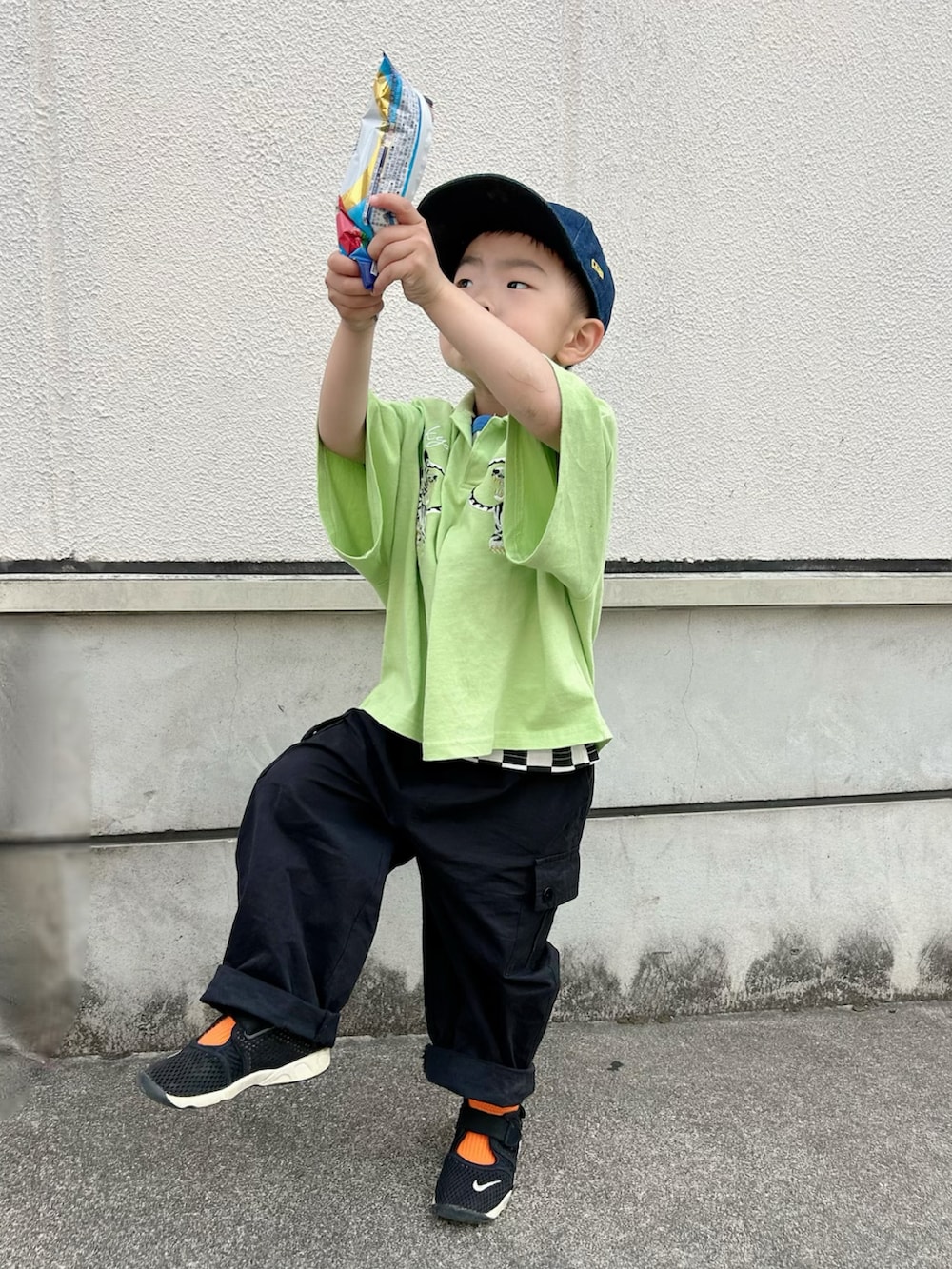 ブラック系のタンクトップ、グリーン系のポロシャツ、ブラック系のカーゴパンツを着用したキッズの春コーディネートの2枚目の写真