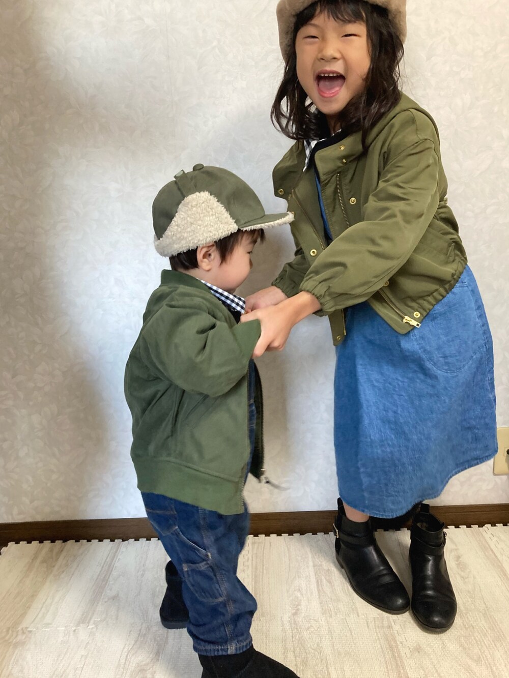 グリーン系のブルゾン、ブルー系のサロペット/オーバーオール、ブルー系のジャンパースカートを着用したキッズの冬コーディネートの4枚目の写真