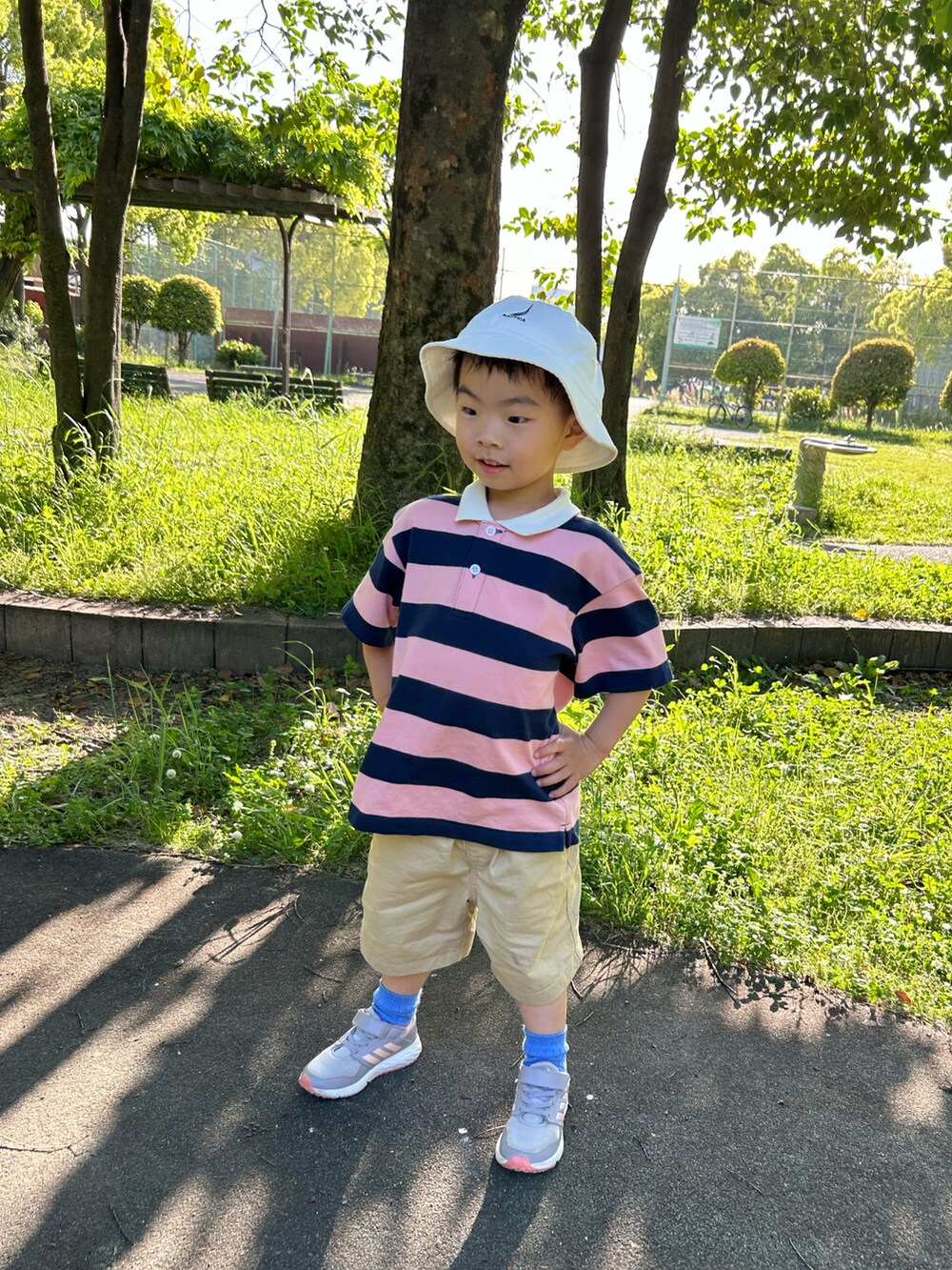 ピンク系のポロシャツ、ベージュ系のチノパンツ、ホワイト系のスニーカーを着用したキッズの春コーディネートの5枚目の写真