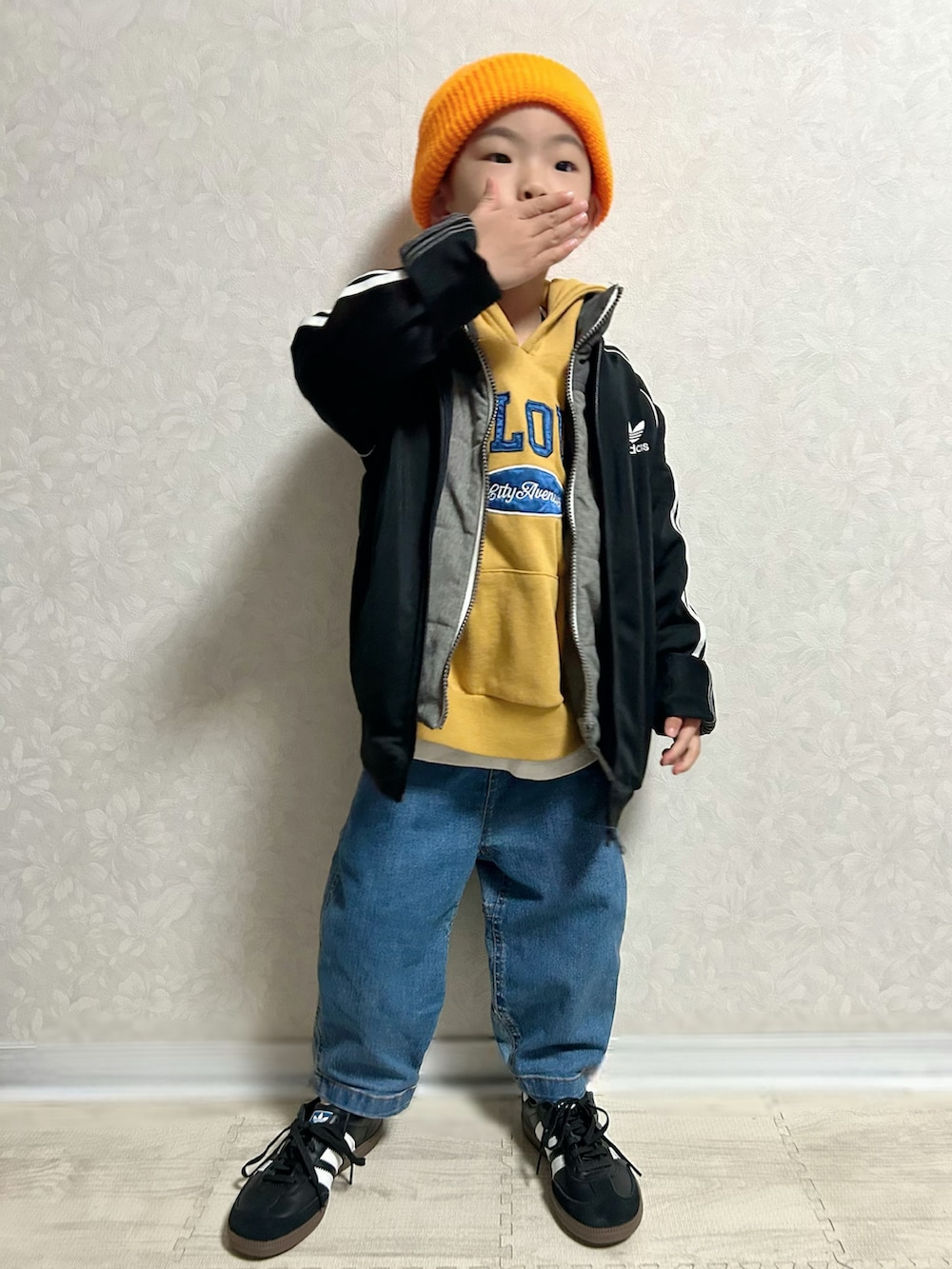 イエロー系のパーカー、グレー系のダウンベスト、ブラック系のジャージを着用したキッズの冬コーディネートの2枚目の写真