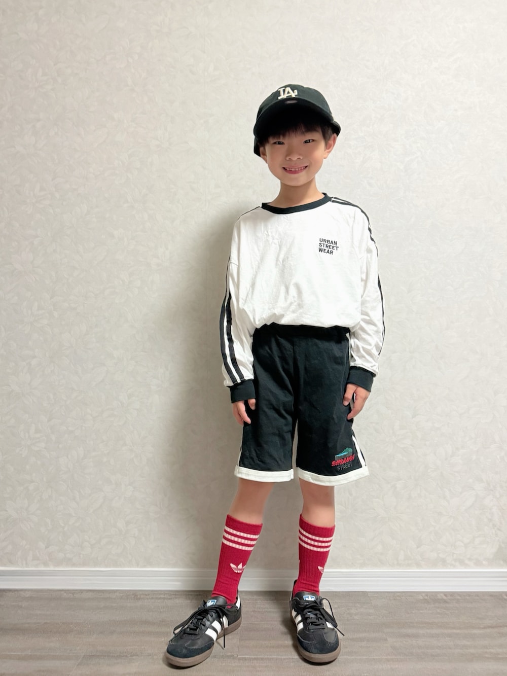 ブラック系のセットアップ、ホワイト系のTシャツ/カットソー、ブラック系のキャップを着用したキッズの秋コーディネートの3枚目の写真