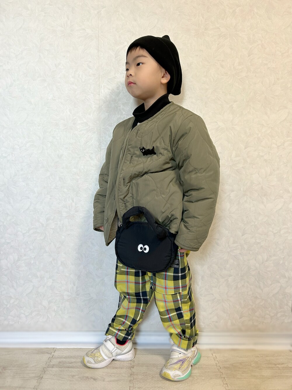 ブラック系のTシャツ/カットソー、ホワイト系のニット/セーター、グリーン系のノーカラージャケットを着用したキッズの冬コーディネートの4枚目の写真