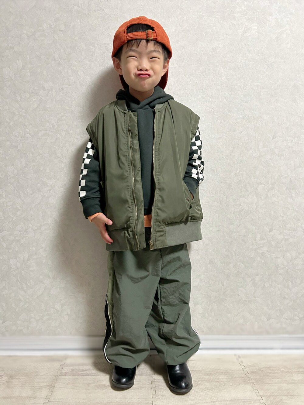 オレンジ系のTシャツ/カットソー、ブラック系のパーカー、グリーン系のMA-1を着用したキッズの秋コーディネートの3枚目の写真