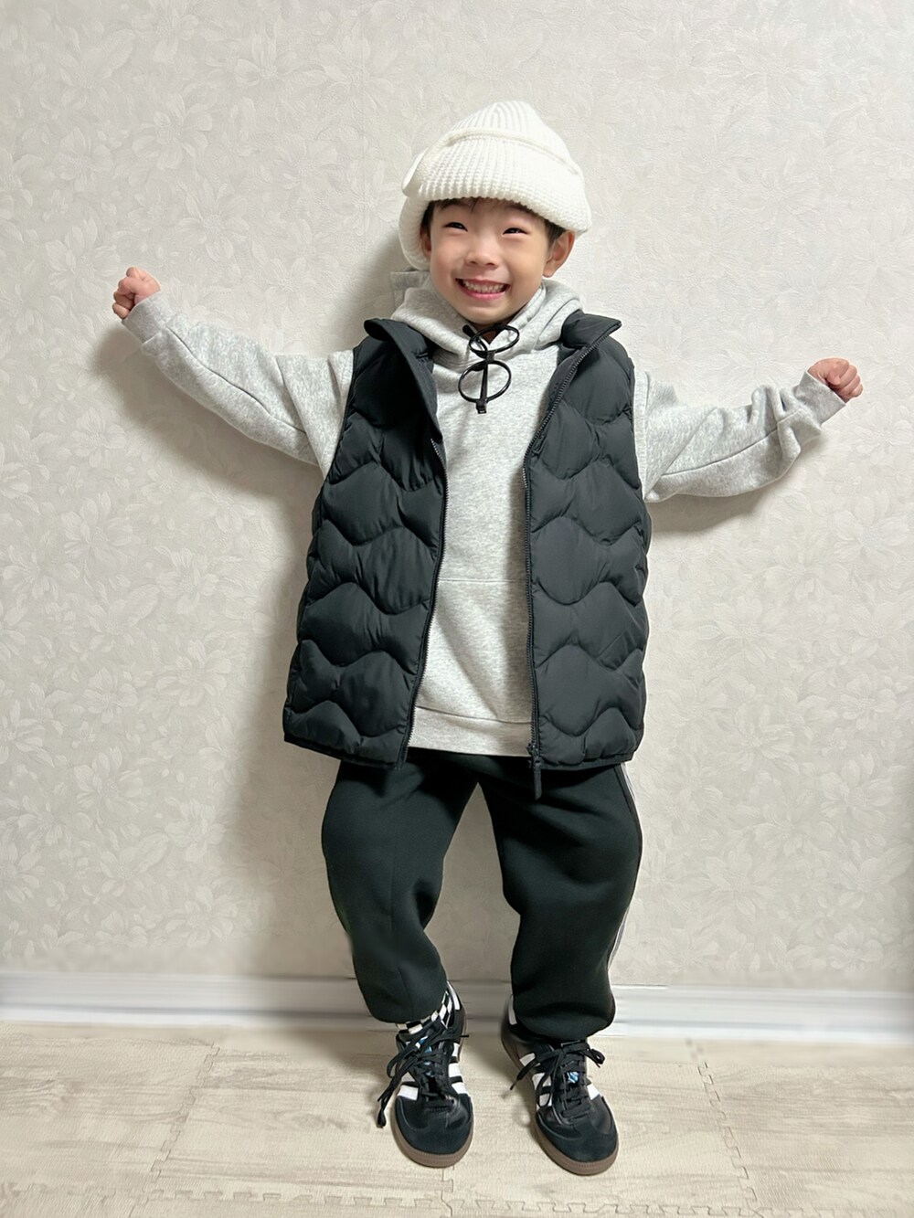グレー系のパーカー、ブラック系のダウンベスト、ブラック系のセットアップを着用したキッズの冬コーディネートの3枚目の写真