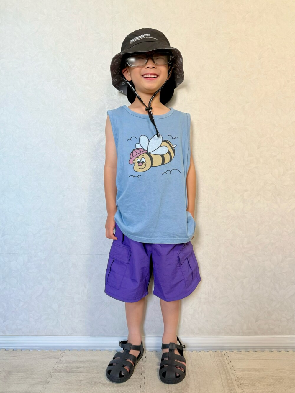 パープル系のカーゴパンツ、ブラック系のサンダル、ブルー系のタンクトップを着用したキッズの夏コーディネートの2枚目の写真