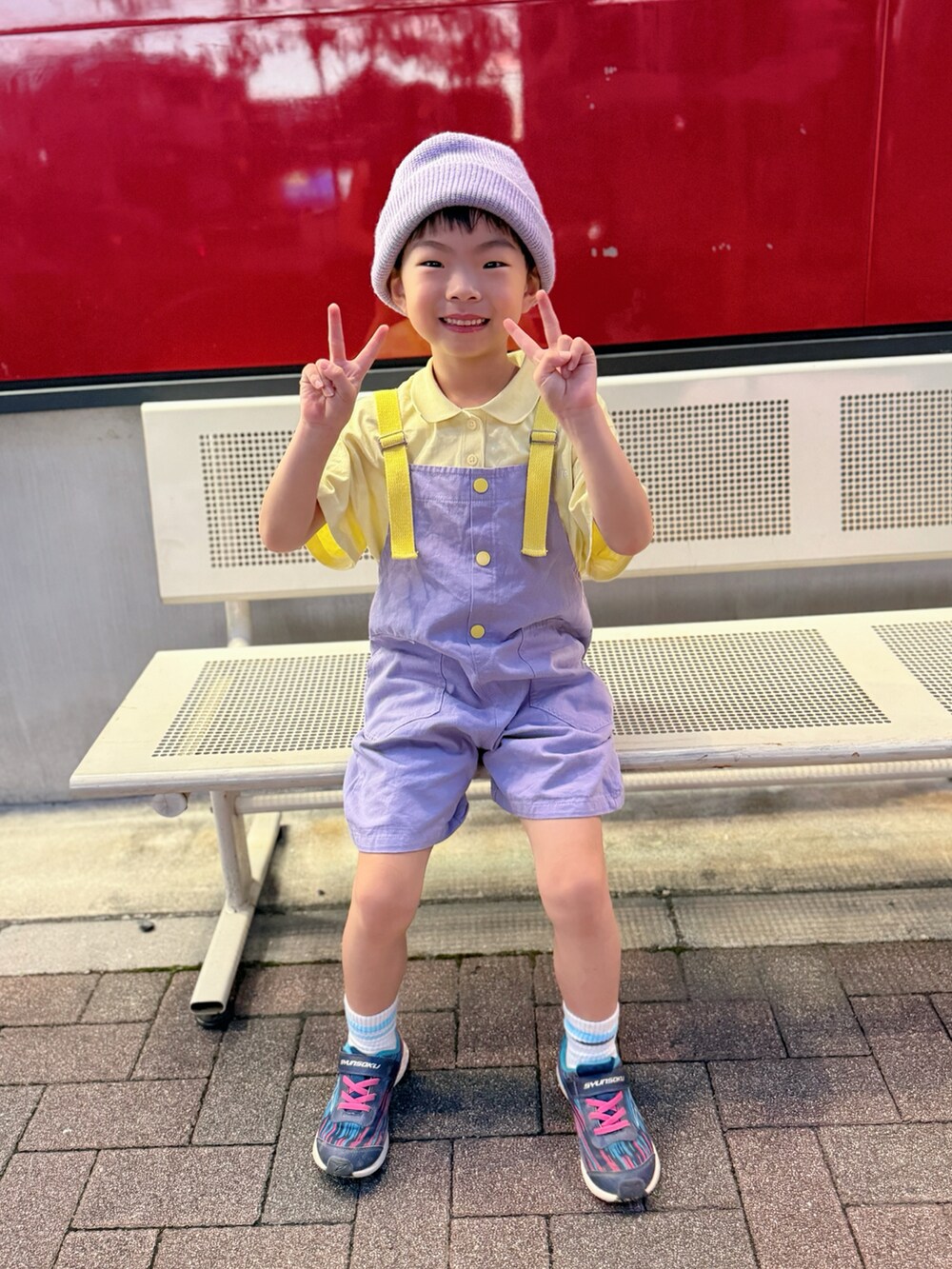 ブルー系のスニーカー、イエロー系のポロシャツ、パープル系のサロペット/オーバーオールを着用したキッズの秋コーディネートの4枚目の写真