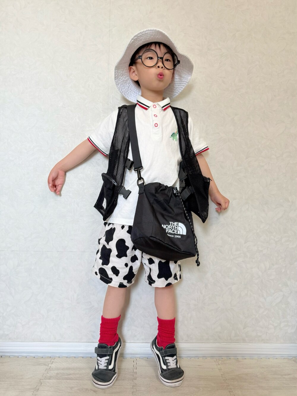 ホワイト系のポロシャツ、ホワイト系のパンツ、ブラック系のベストを着用したキッズの春コーディネートの3枚目の写真