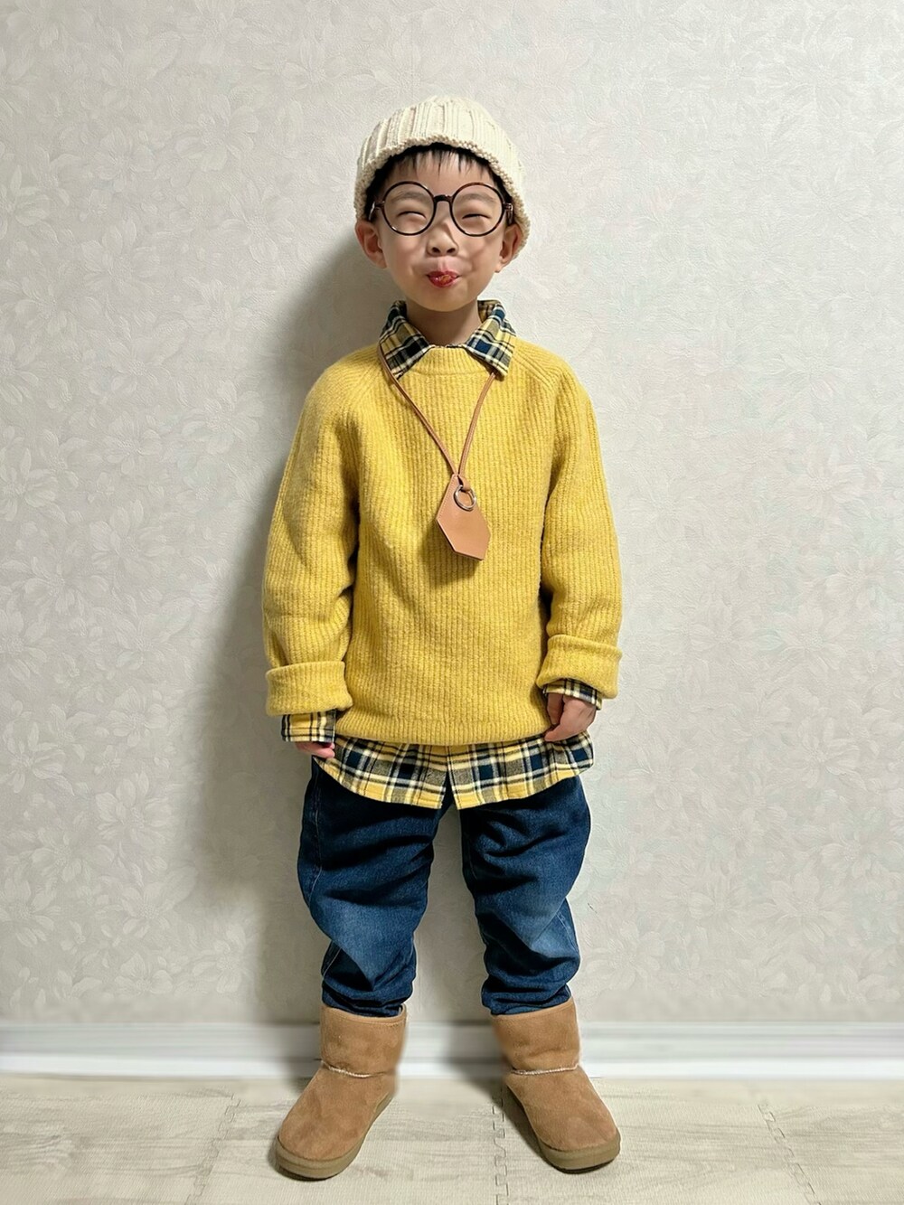 イエロー系のニット/セーター、イエロー系のシャツ/ブラウス、ブルー系のデニムパンツを着用したキッズの冬コーディネートの2枚目の写真