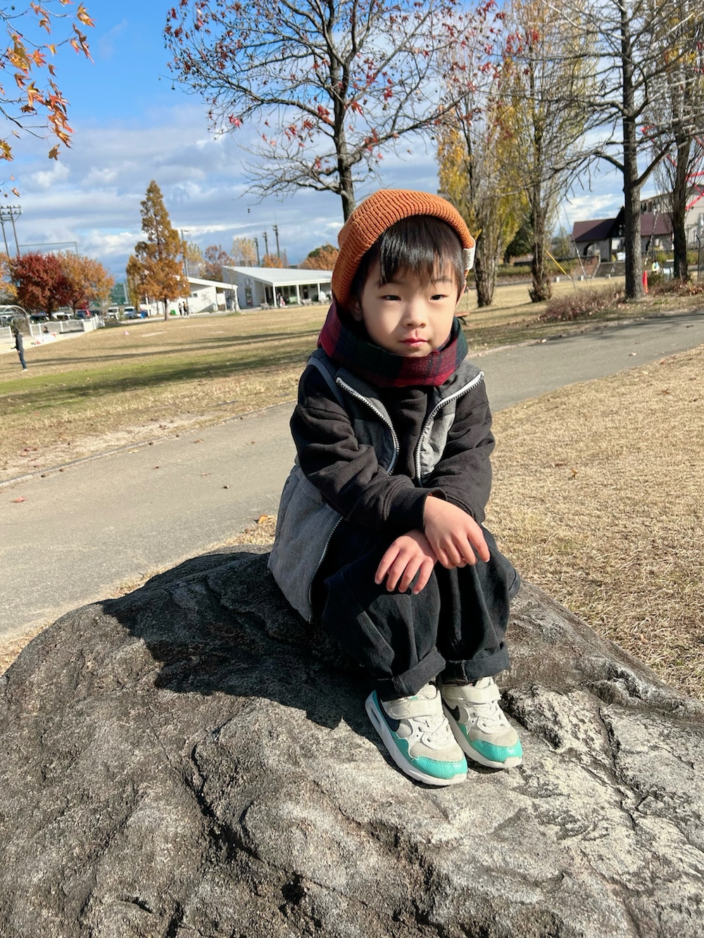 オレンジ系のスウェット、グレー系のスウェット、グレー系のダウンベストを着用したキッズの冬コーディネートの5枚目の写真