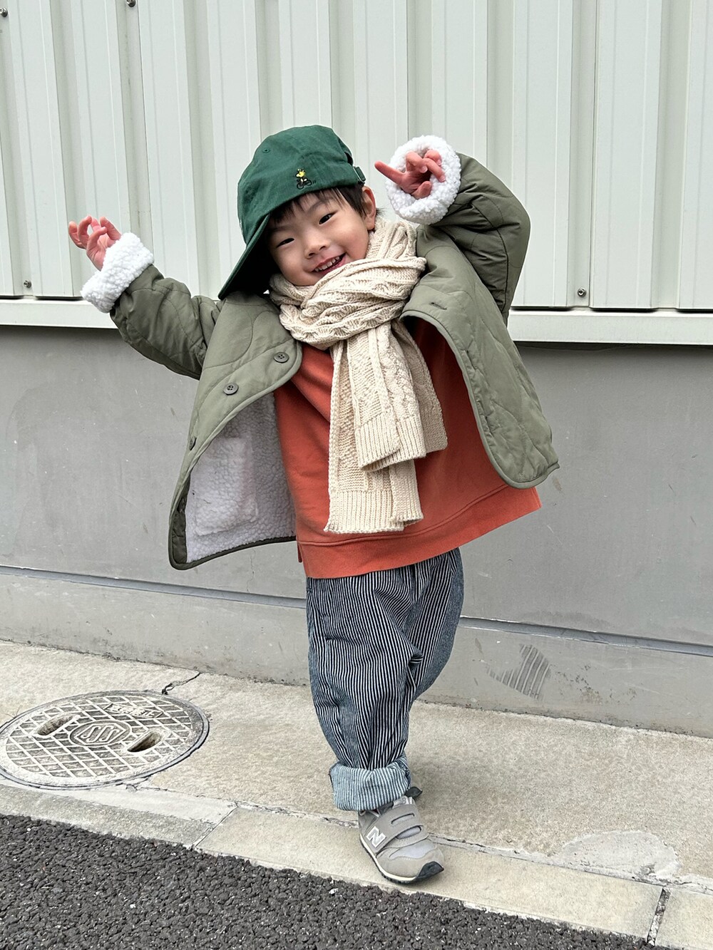 オレンジ系のスウェット、グリーン系のノーカラージャケット、ブルー系のデニムパンツを着用したキッズの冬コーディネートの5枚目の写真