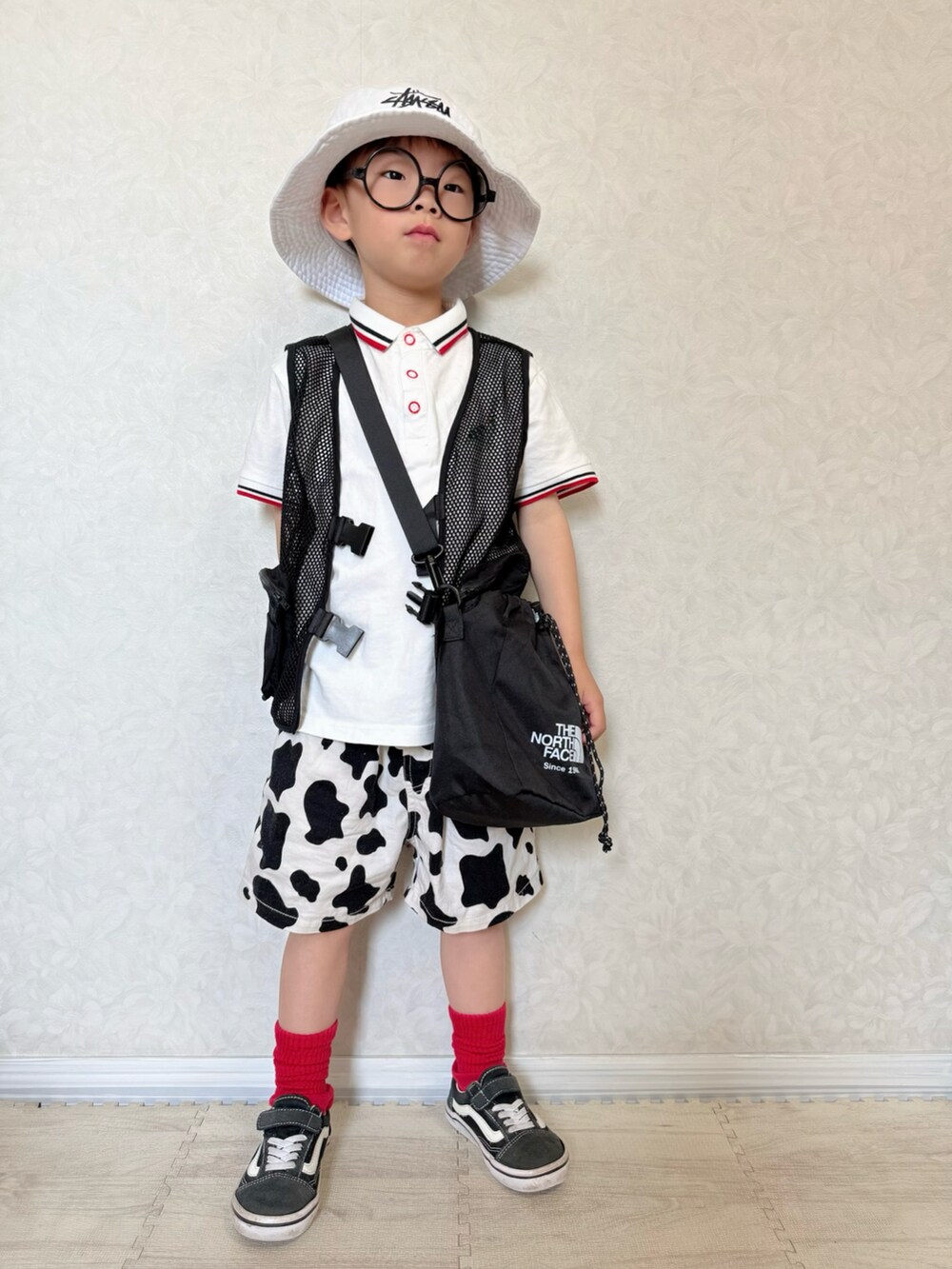ホワイト系のポロシャツ、ホワイト系のパンツ、ブラック系のベストを着用したキッズの春コーディネートの2枚目の写真